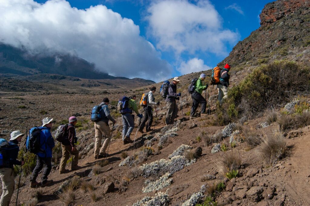 Travellers hiking a rocky mountain trail with a guide